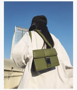 Close-up of olive green matte leather crossbody bag with large silver metal buckle detail