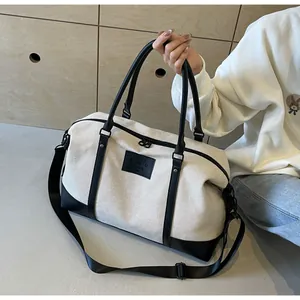 Detail of off-white travel bag with black leather trim and adjustable nylon shoulder strap