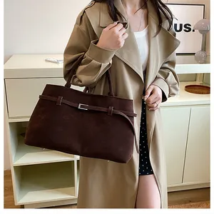 Détail de la texture suédée marron foncé et de la boucle métallique sur le grand sac cabas