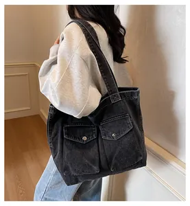 Détail d'un grand sac cabas en jean noir avec poches cargo et boutons métalliques