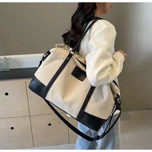 Close-up of canvas travel bag featuring black leather trim and adjustable shoulder strap