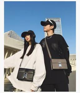 Detail of a black crossbody bag with silver buckle set against an urban sky background