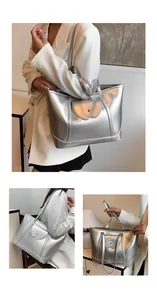 Close-up of a large silver metallic tote bag featuring a magnetic buckle and wavy flap