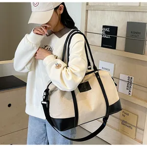 Detail of canvas tote bag with black leather trim and adjustable shoulder strap worn by model