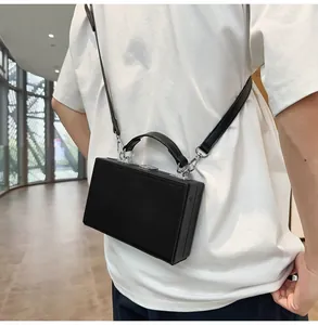 Male model wearing a black hard-shell box bag in a minimalist architectural setting