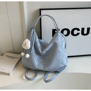 Détail du sac cabas bleu clair à motif marbré avec breloque nuage et logo de la marque