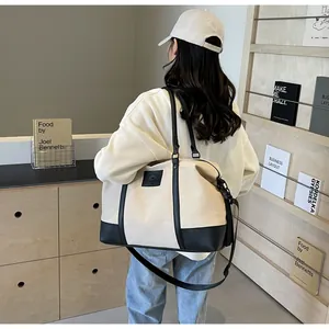Detailed side view of model wearing a large canvas travel bag with black leather base