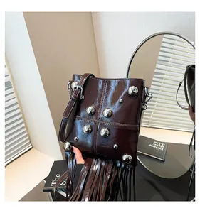 Dettaglio borsa in pelle oleata marrone scuro con borchie argentate e frange