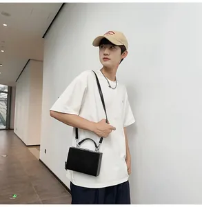 Close-up of a minimalist black hardshell box bag with a leather handle and silver buckles