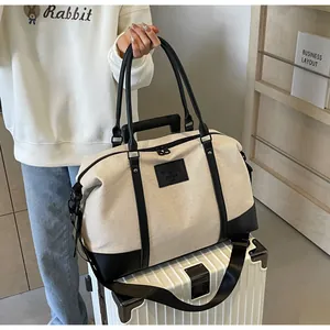 Detail of canvas travel bag with leather handles and adjustable shoulder strap