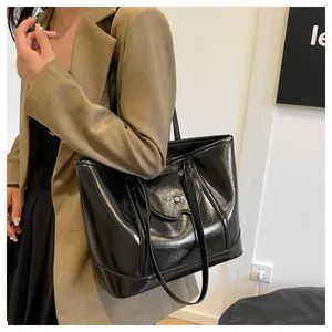 Close-up of black glossy patent leather tote bag with magnetic pocket on a model