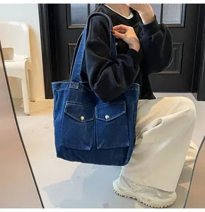 Vue détaillée du sac en jean avec deux poches à rabat et des accents de boutons en métal