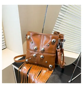 Dettaglio della borsa a tracolla in pelle marrone con borchie argentate e lunghe frange