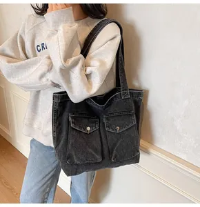 Détail du sac cabas en jean noir avec poches cargo et boutons argentés sur modèle