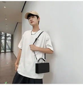 Detailed look of white cotton t-shirt paired with black hard-shell box bag and silver chain