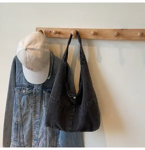 Detail view of large dark grey denim hobo bag with metal snap button closure