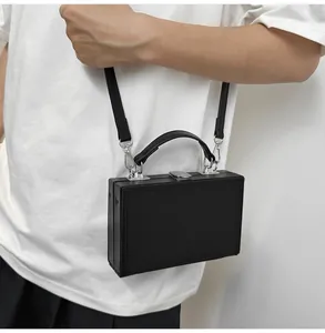 Close-up of black hard-shell box bag featuring silver metallic lock and smooth leather texture