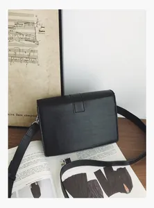 Detail of black rectangular crossbody bag with litchi texture and buckle strap