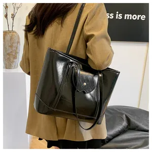 Detail of black glossy leather tote bag with metallic buckle pocket and shoulder strap
