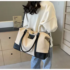 Detail of cream canvas travel bag with black leather straps and adjustable shoulder strap