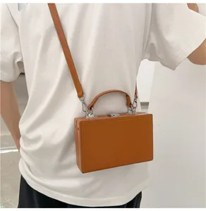 Close-up of the brown leather mini box bag showing detailed stitching and silver metal buckle