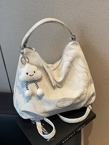 Sac fourre-tout à motif marbre avec pendentif nuage posé sur un livre noir décoratif