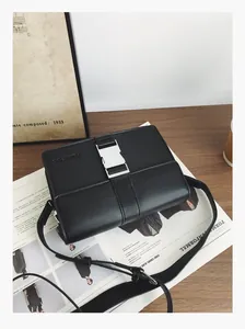 Detailed view of black faux leather crossbody bag with silver buckle and adjustable strap
