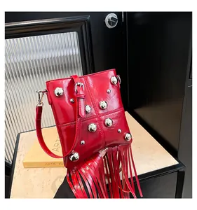 Detalle del bolso rojo brillante con remaches plateados y flecos de borlas largas suaves