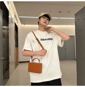 Brown hard-shell box bag for men worn with a white cotton T-shirt in modern interior