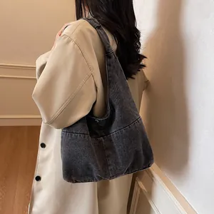 Black washed denim large capacity hobo shoulder bag styled with a beige trench coat