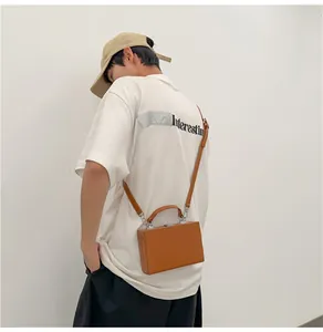 Brown hard-shell mini suitcase bag shown on model with adjustable shoulder strap