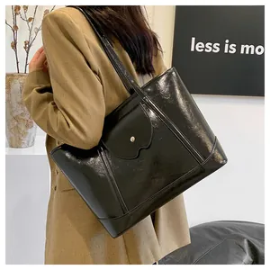 Detail of glossy black leather tote bag with wavy front pocket and large capacity for women