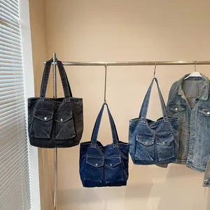 Trois couleurs de sacs cabas en jean avec poches à rabat sur un support en métal