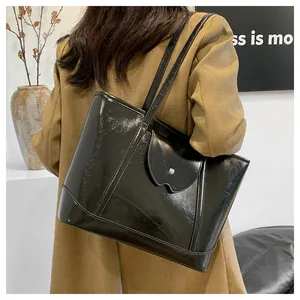 Close-up of black glossy leather tote bag with petal flap pocket and silver buckle detail