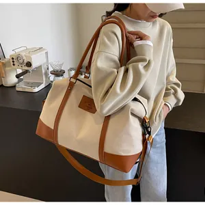 Detail of canvas travel bag with leather accents and adjustable shoulder strap worn by model
