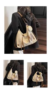 Detail of beige canvas tote with brown leather trim, metal rivets and mini pouch