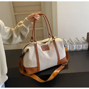Detail of canvas travel bag with brown leather trim and removable shoulder strap