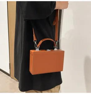 Close-up of caramel hard-shell box bag showing leather texture and silver hardware details