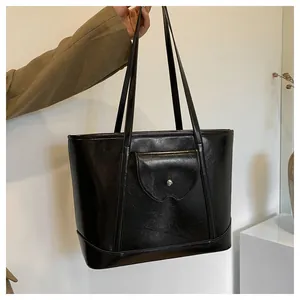 Detail of black faux leather tote bag with vintage oil-wax texture and front flap pocket