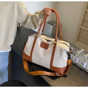 Close-up of cream canvas travel bag with brown leather handles and yellow shoulder strap