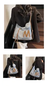 Detail of blue denim hobo bag with brown leather trim and metal rivet M letter decoration