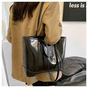 Close-up of minimalist black shiny oil wax leather tote bag with semi-circle flap detail