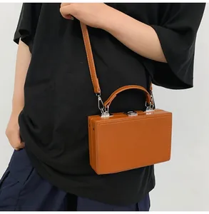 Brown matte faux leather box bag with silver hardware worn cross-body by a male model