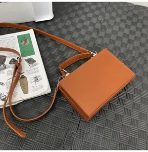Detailed top view of a brown box-style crossbody bag with double stitching and long strap