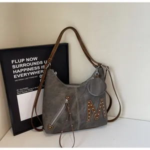 Detail of grey vintage tote bag with letter M embroidery, rivets and small round coin purse