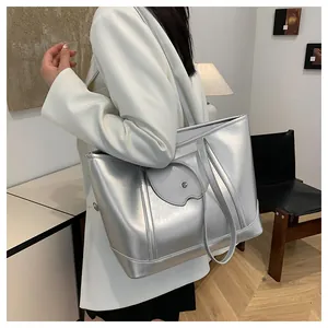 Metallic silver tote bag shown as a shoulder bag with a unique heart-shaped front pocket