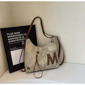 Macro detail of beige tote bag with brown leather M patch and metal rivets