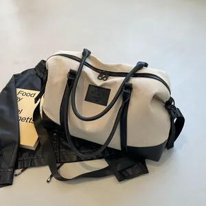 Cream canvas travel bag with black leather trim and shoulder strap in a stylish setup