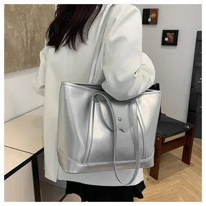 Detail of silver metallic tote bag featuring wavy flap pocket and dual shoulder straps