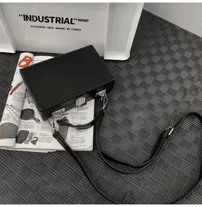 Detail of a black matte hard-shell box bag with silver metal lock and thin strap